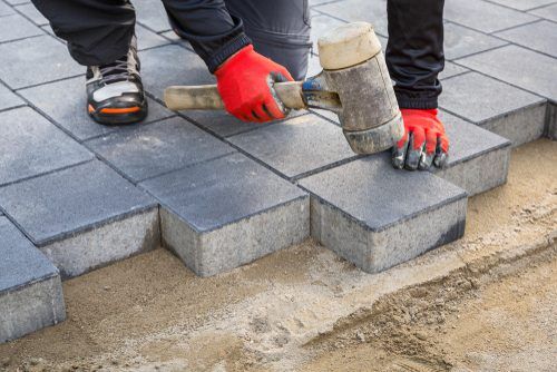 Hands,Of,Worker,Installing,Concrete,Paver,Blocks,With,Rubber,Hammer