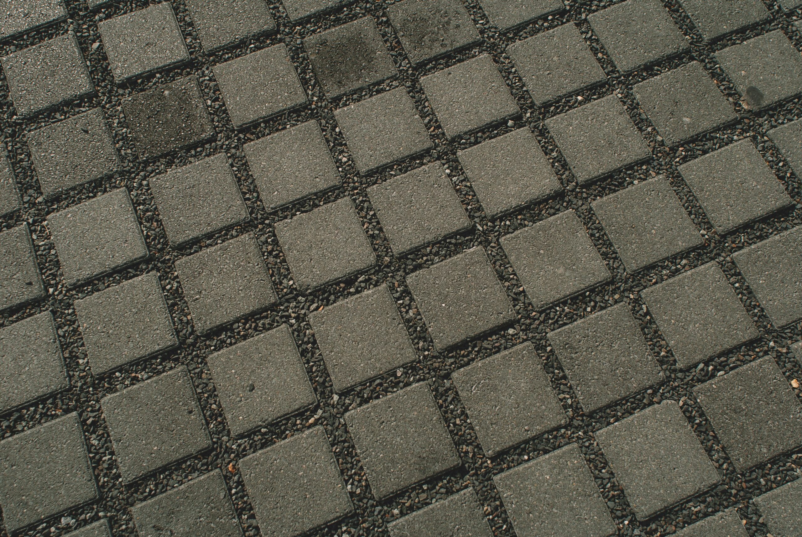 Permeable pavers vs non permeable pavers concept shown through a close-up of permeable paver blocks with gravel-filled joints for drainage.